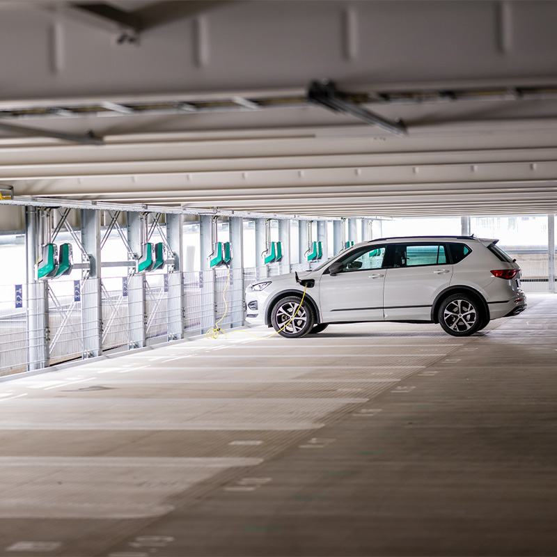 Innenansicht des Parkhauses am Hirschgarten mit Wandlandestationen und einem Auto