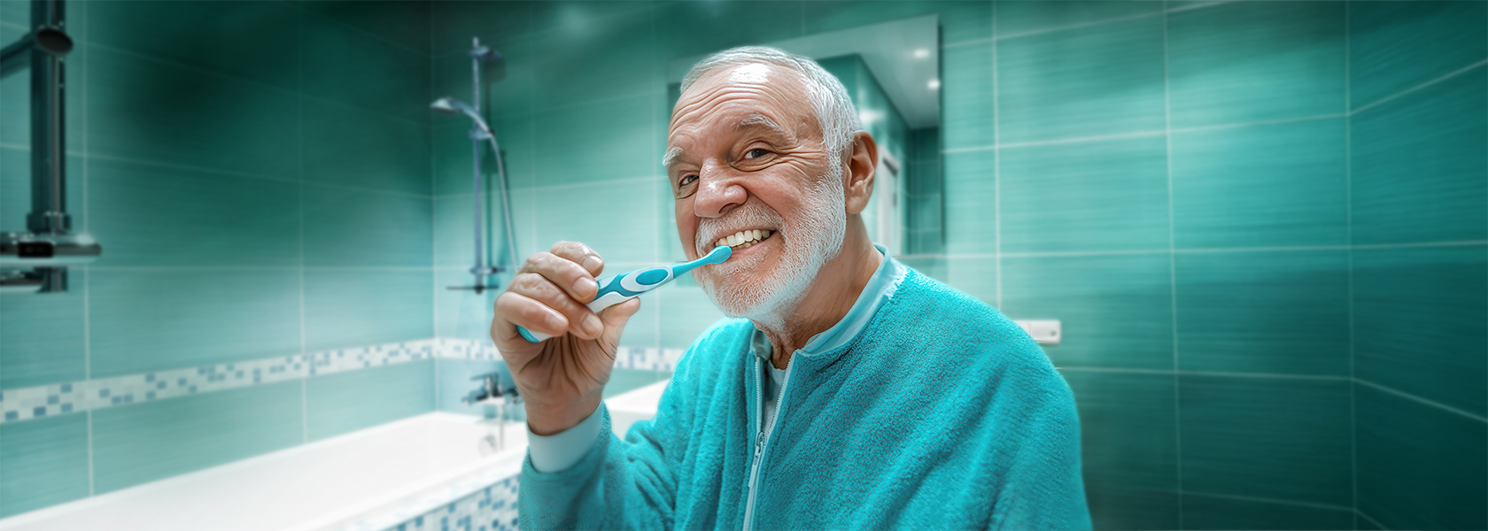 Älterer Mann im Badezimmer, der sich mit einer elektrischen Zahnbürste die Zähne putzt.