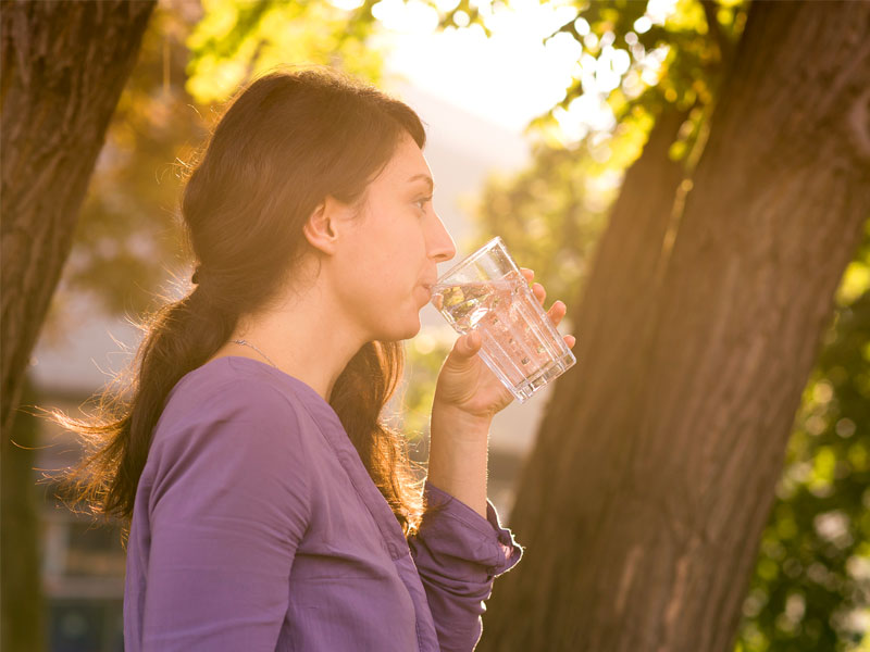 Eine Frau die ein Glas Wasser trinkt.