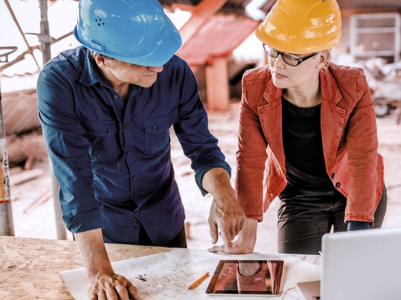 Zwei Personen mit Bauhelmen im Gespr&auml;ch.